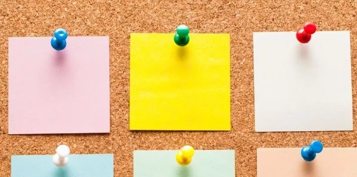 A pin board with post-it notes pinned to it