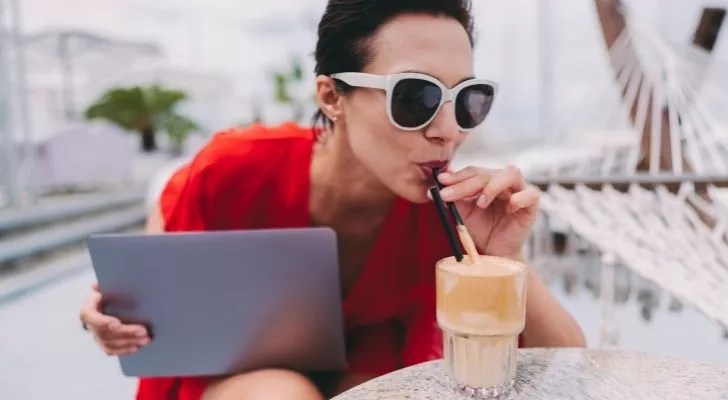 A woman drinking a frappé while working on her iPad