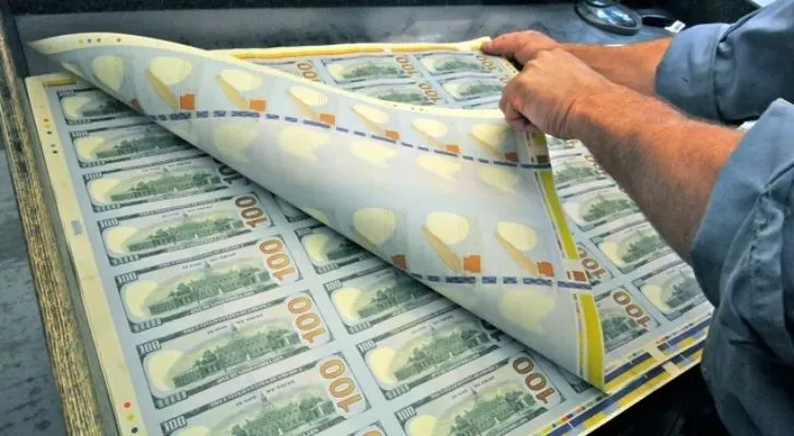 A person inspecting $100 paper bills.