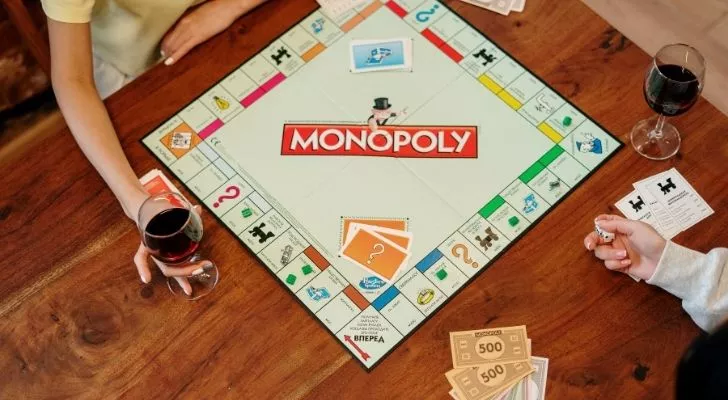 Two people playing monopoly on a wooden table