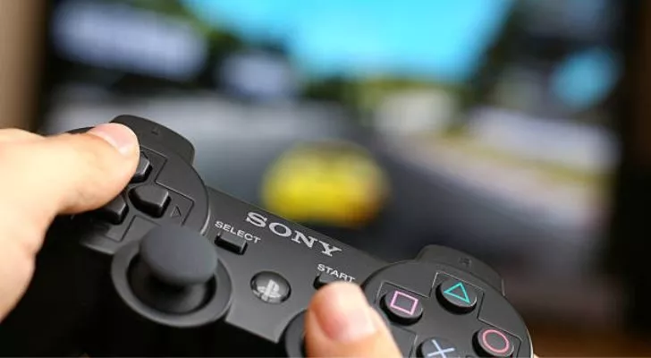A person playing a game holding a PS3 controller. 